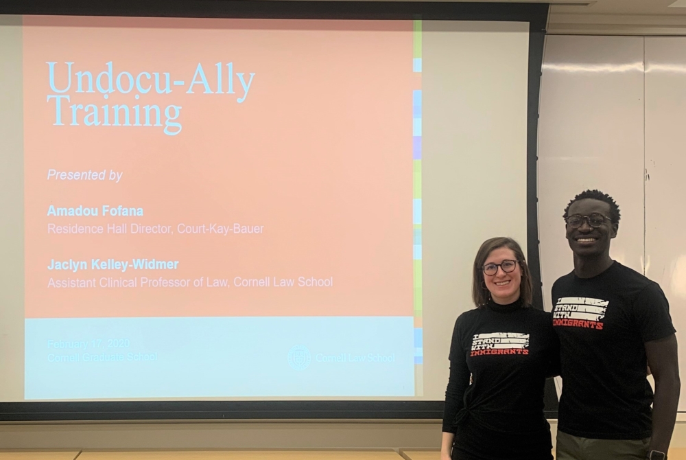 a man and a woman stand in front of a PowerPoint screen that reads “Undocu-Ally Training.”
