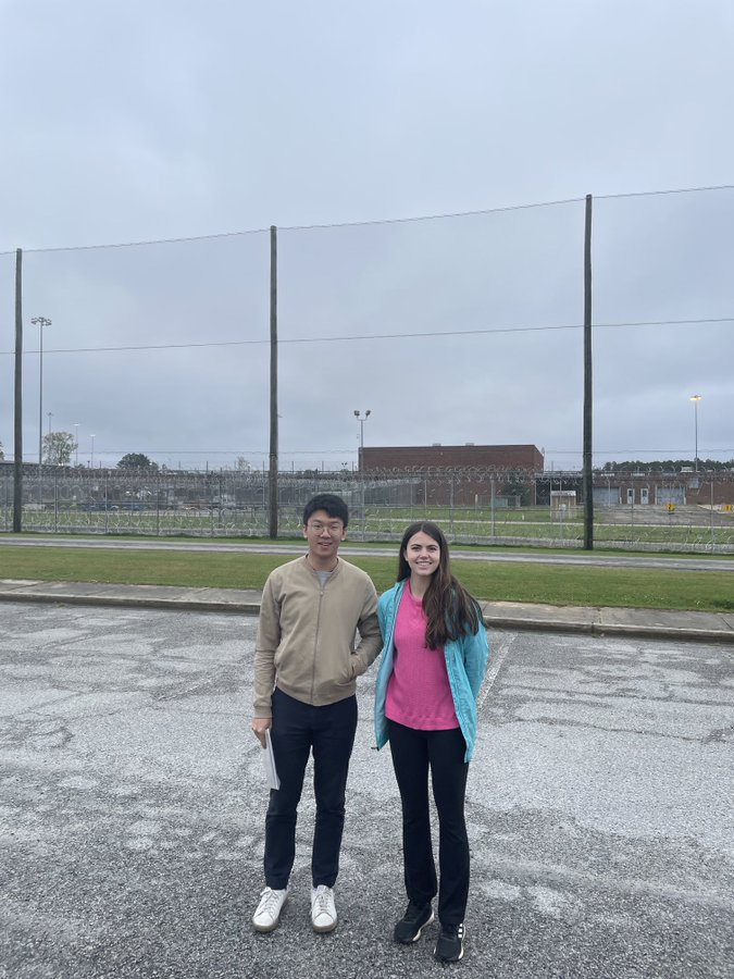 two students in front of a prison complex